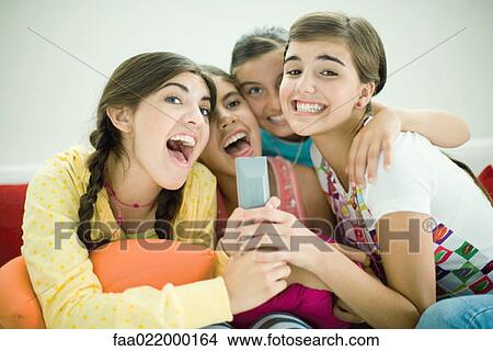 Young female friends sitting together, singing into remote control View Large Photo Image Picture - Young female friends sitting together, singing into remote control. Fotosearch