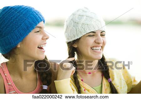 Stock Image - Young female friends wearing knit hats, laughing. Fotosearch