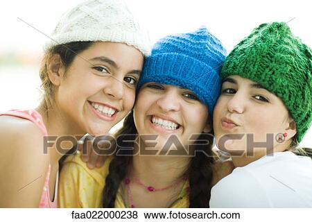 Stock Photo - Young female friends wearing knit hats, smiling at camera. Fotosearch