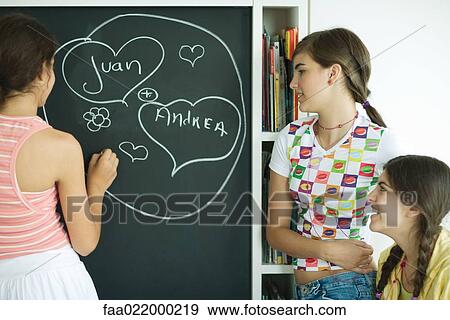 Young female friends writing names in hearts on chalkboard View Large Photo Image Stock Photo - Young female friends writing names in hearts on chalkboard. Fotosearch