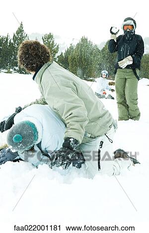 Stock Image - Young friends having snowball fight in snow. Fotosearch