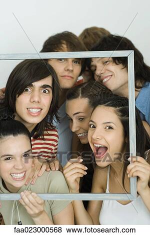 Young friends holding up frame together, smiling at camera View Large Photo Image Stock Photo - Young friends holding up frame together, smiling at camera. Fotosearch