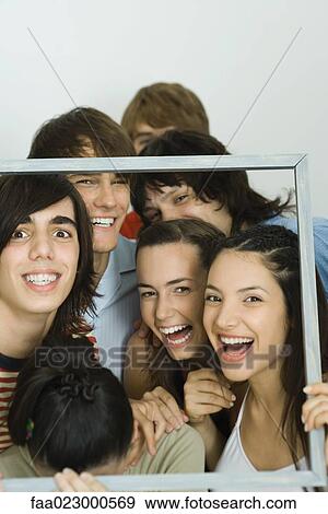 Young friends holding up frame together, smiling at camera View Large Photo Image Stock Photo - Young friends holding up frame together, smiling at camera. Fotosearch