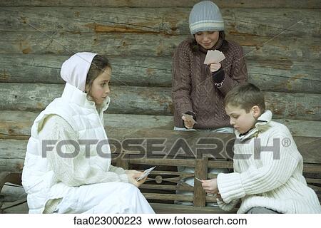 Young friends in winter clothes playing cards View Large Photo Image Stock Image - Young friends in winter clothes playing cards. Fotosearch