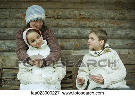 Stock Photo - Young friends in winter clothes playing cards. Fotosearch