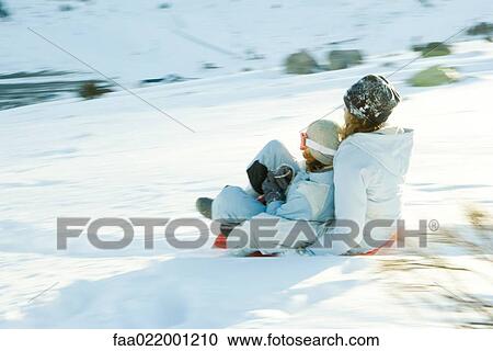Stock Image - Young friends sledding down hill together, blurred motion. Fotosearch