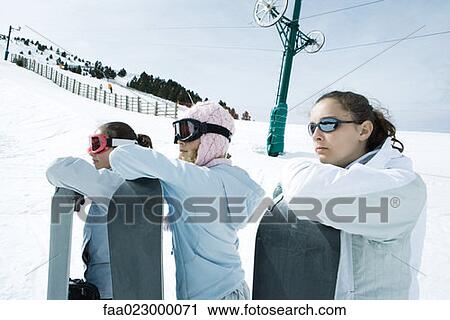 Young friends standing together, holding snowboards, looking away View Large Photo Image Stock Image - Young friends standing together, holding snowboards, looking away. Fotosearch