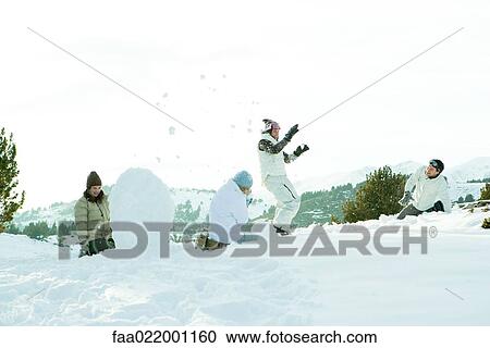 Stock Image - Young friends throwing snowballs at each other, full length. Fotosearch