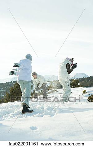 Young friends throwing snowballs at each other, full length View Large Photo Image Stock Image - Young friends throwing snowballs at each other, full length. Fotosearch