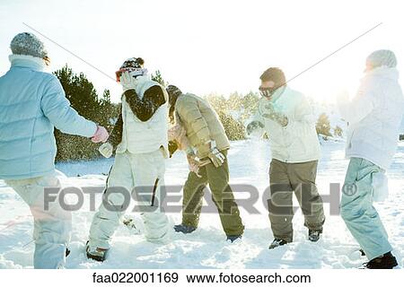Young friends throwing snowballs at each other, full length View Large Photo Image Stock Photo - Young friends throwing snowballs at each other, full length. Fotosearch
