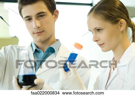 Young male and female scientists holding test tube and flask View Large Photo Image Picture - Young male and female scientists holding test tube and flask. Fotosearch