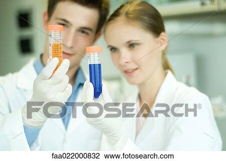 Young male and female scientists holding up test tubes View Large Photo Image Stock Image - Young male and female scientists holding up test tubes. Fotosearch