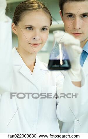 Young male and female scientists, woman holding up dropper and flask View Large Photo Image Stock Image - Young male and female scientists, woman holding up dropper and flask. Fotosearch