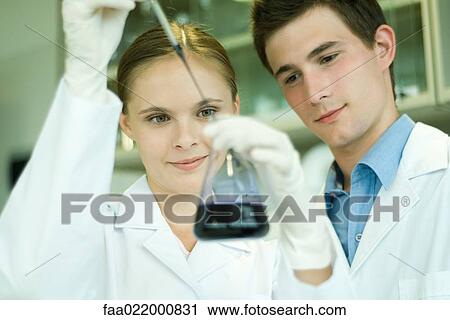 Young male and female scientists, woman holding up dropper and flask View Large Photo Image Stock Image - Young male and female scientists, woman holding up dropper and flask. Fotosearch