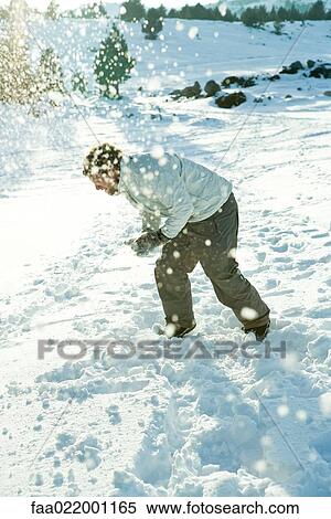 Young man bending over in snow, dodging snowball, full length View Large Photo Image Stock Photography - Young man bending over in snow, dodging snowball, full length. Fotosearch