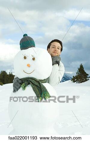 Young man embracing snowman, hand under chin, portrait View Large Photo Image Stock Image - Young man embracing snowman, hand under chin, portrait. Fotosearch