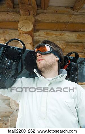 Young man holding snowboard on shoulder, low angle view, portrait View Large Photo Image Stock Image - Young man holding snowboard on shoulder, low angle view, portrait. Fotosearch