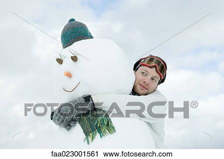 Young man hugging snowman View Large Photo Image Stock Image - Young man hugging snowman. Fotosearch
