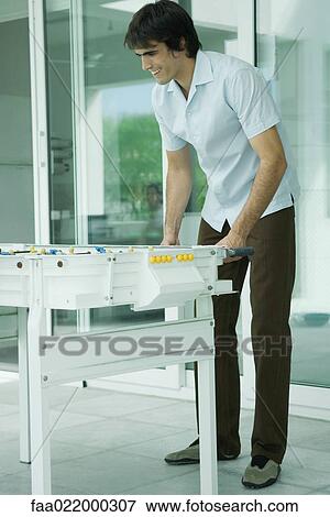 Young man playing foosball, full length View Large Photo Image Stock Photo - Young man playing foosball, full length. Fotosearch
