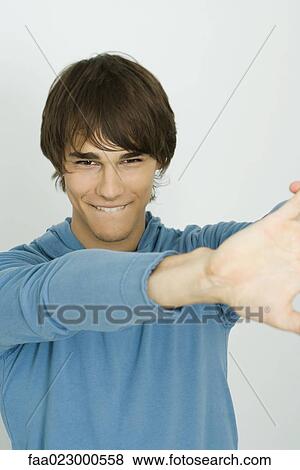 Young man smiling at camera, biting lip, portrait View Large Photo Image Stock Photo - Young man smiling at camera, biting lip, portrait. Fotosearch