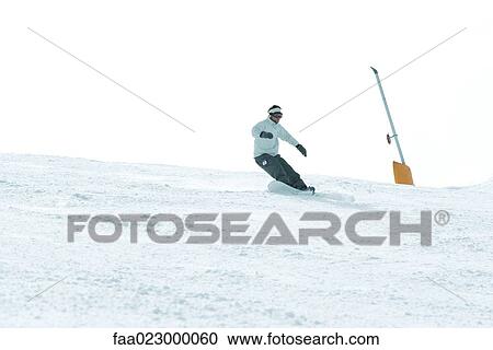 Young man snowboarding down ski slope, full length View Large Photo Image Stock Image - Young man snowboarding down ski slope, full length. Fotosearch