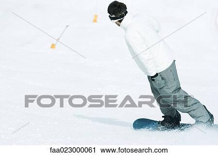Young man snowboarding down ski slope, rear view View Large Photo Image Stock Image - Young man snowboarding down ski slope, rear view. Fotosearch