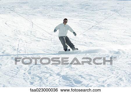 Young man snowboarding down ski slope, full length View Large Photo Image Stock Photograph - Young man snowboarding down ski slope, full length. Fotosearch