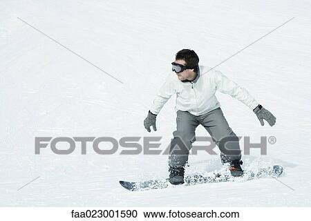 Stock Image - Young man snowboarding, full length. Fotosearch