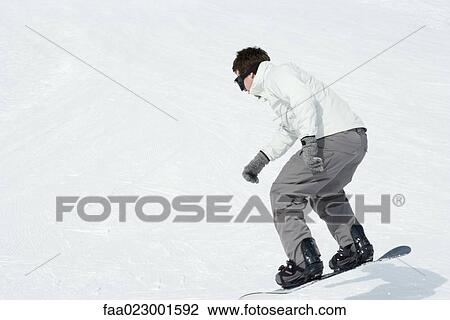 Stock Image - Young man snowboarding, full length. Fotosearch