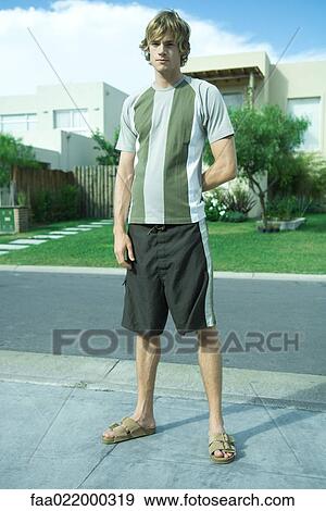 Young man standing in residential neighborhood, full length portrait View Large Photo Image Stock Photo - Young man standing in residential neighborhood, full length portrait. Fotosearch