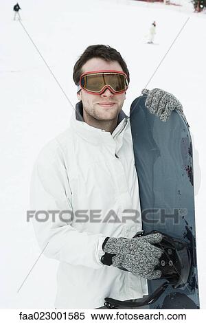 Young man standing with snowboard, portrait View Large Photo Image Stock Photography - Young man standing with snowboard, portrait. Fotosearch