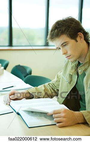 Stock Image - Young man studying in university library. Fotosearch