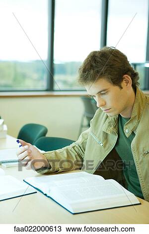 Young man studying in university library View Large Photo Image Stock Image - Young man studying in university library. Fotosearch