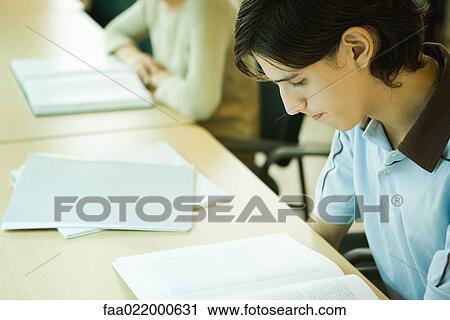 Stock Image - Young man studying in university library. Fotosearch