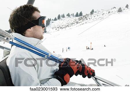 Stock Image - Young man taking ski lift. Fotosearch