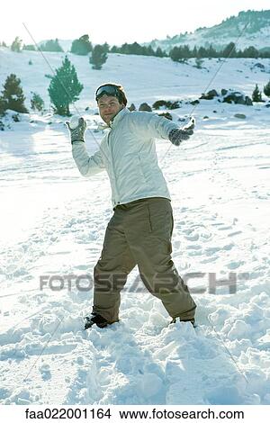 Picture - Young man throwing snowball, smiling at camera, full length. Fotosearch