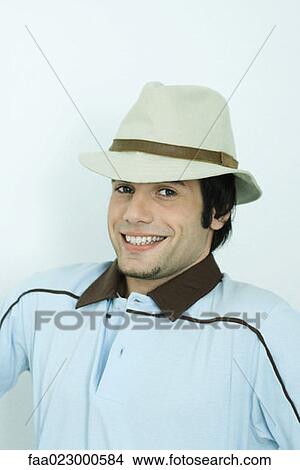 Young man wearing hat, smiling at camera, portrait View Large Photo Image Picture - Young man wearing hat, smiling at camera, portrait. Fotosearch