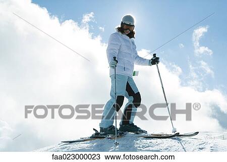 Young skier on top of hill, full length portrait, low angle view View Large Photo Image Stock Image - Young skier on top of hill, full length portrait, low angle view. Fotosearch