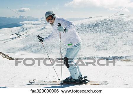Stock Photograph - Young skier smiling at camera, full length portrait. Fotosearch