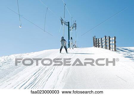 Young skiers going up hill on ski lift, rear view View Large Photo Image Stock Image - Young skiers going up hill on ski lift, rear view. Fotosearch