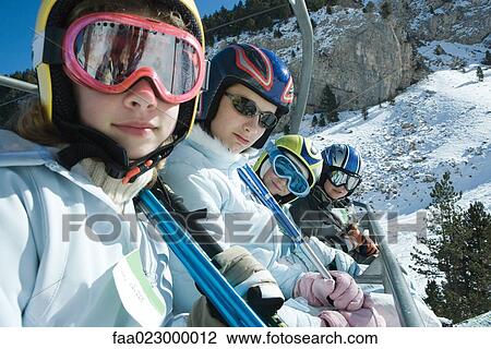 Young skiers on chair lift, smiling at camera View Large Photo Image Stock Image - Young skiers on chair lift, smiling at camera. Fotosearch