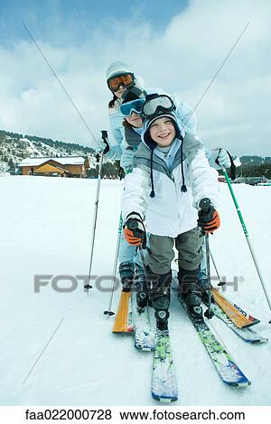 Stock Photo - Young skiers on snow, smiling at camera, full length, portrait. Fotosearch