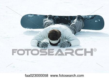 Young snowboarder lying on stomach in snow, full length View Large Photo Image Stock Photo - Young snowboarder lying on stomach in snow, full length. Fotosearch