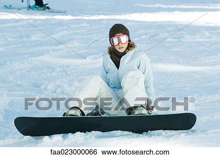 Young snowboarder sitting on the ground, looking at camera, full length View Large Photo Image Stock Photograph - Young snowboarder sitting on the ground, looking at camera, full length. Fotosearch