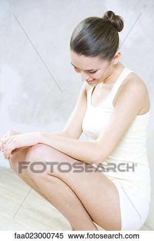 Young woman crouching, dressed in tank top and shorts, head down View Large Photo Image Stock Photography - Young woman crouching, dressed in tank top and shorts, head down. Fotosearch
