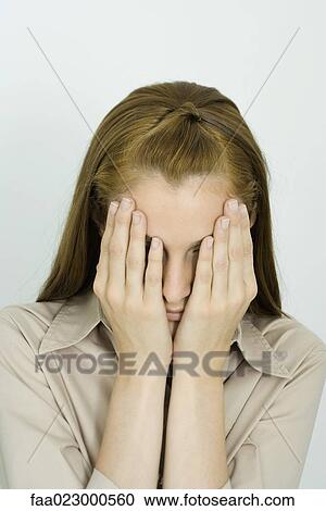 Stock Image - Young woman, hands over face, portrait. Fotosearch