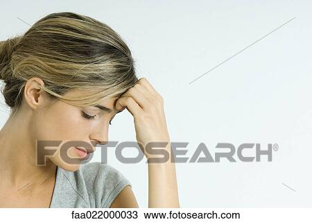 Young woman holding head, looking down, portrait View Large Photo Image Stock Image - Young woman holding head, looking down, portrait. Fotosearch