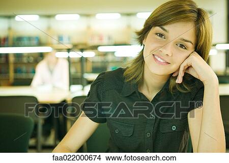 Young woman in university library, smiling at camera View Large Photo Image Picture - Young woman in university library, smiling at camera. Fotosearch