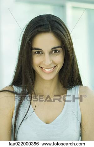 Stock Photograph - Young woman, looking at camera, head and shoulders, front view, portrait. Fotosearch