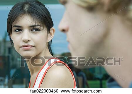 Young woman looking at young man in blurred foreground View Large Photo Image Stock Image - Young woman looking at young man in blurred foreground. Fotosearch